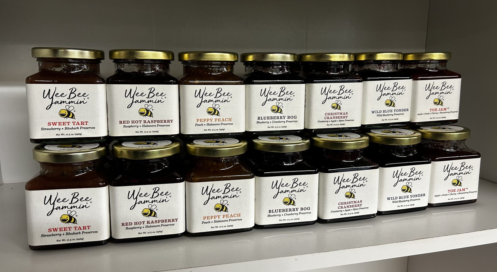Row of Wee Bee Jammin' jam jars including Sweet Tart, Red Hot Raspberry, Peppy Peach, Blueberry Bog, Christmas Cranberry, Wild Blue Yonder, and Toe Jam